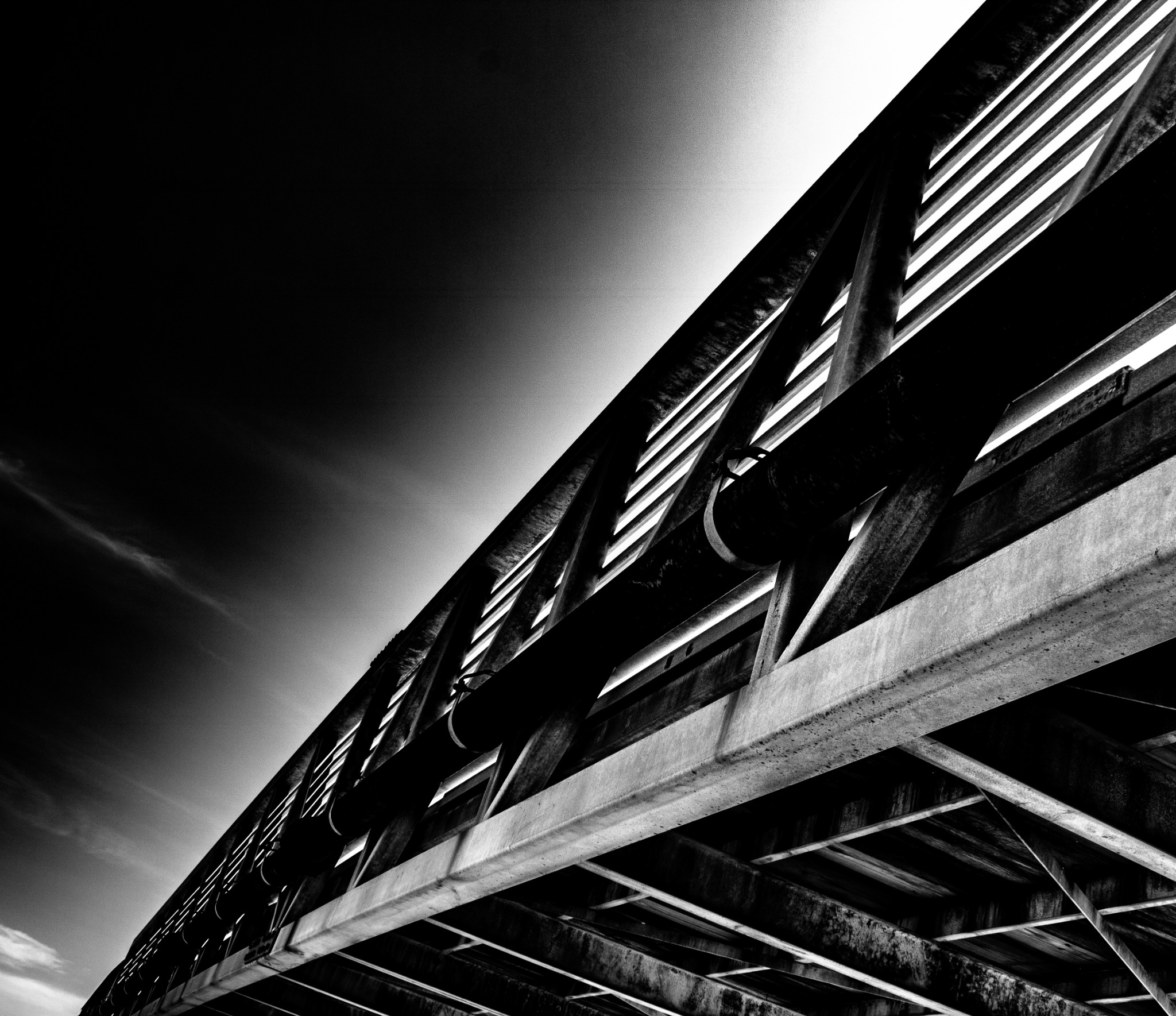 A steel bridge cutting diagonally across a luminous sky